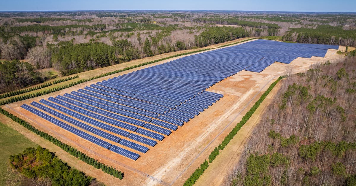 Aerial drone shot of a large solar panel farm in a rural area surrounded by forests in North Carolina.