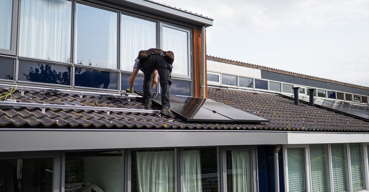 Technician working on installing solar panels on a residential rooftop during the day.