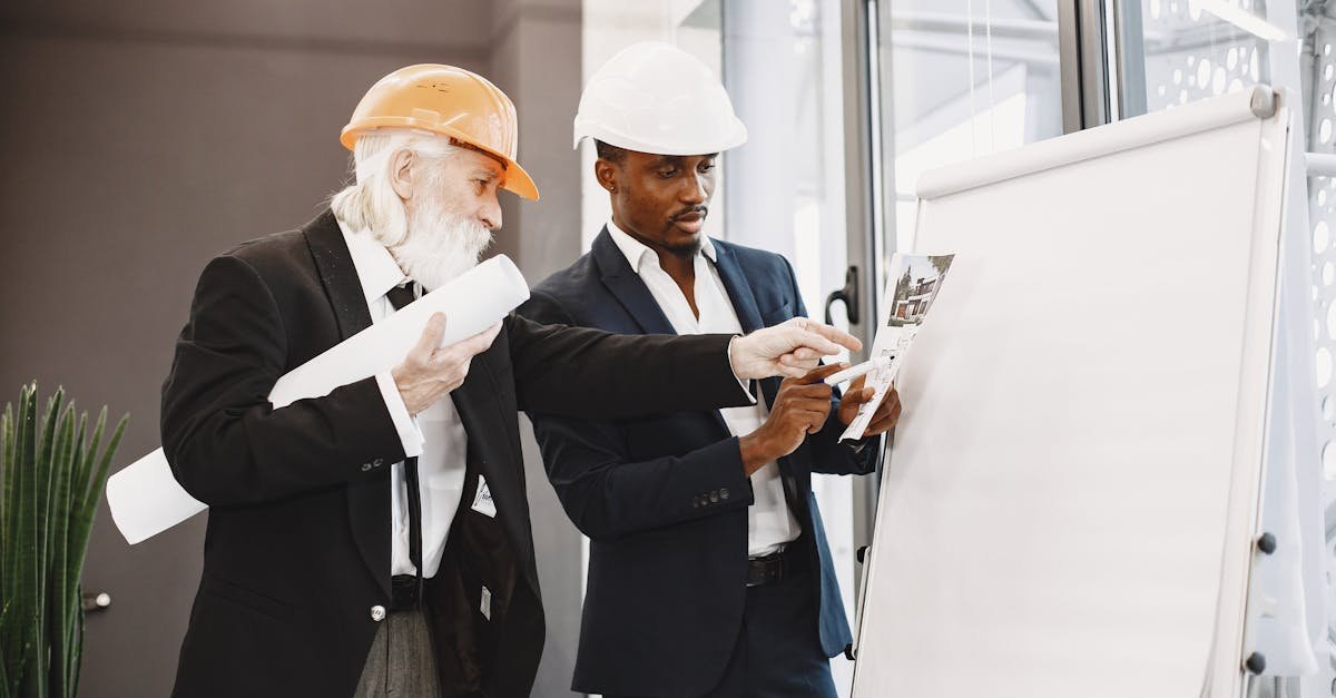 Two engineers discussing blueprints in an office setting.